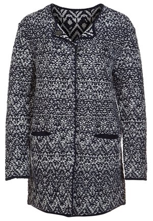 Lange marineblauwe en witte gebreide cardigan met geometrisch patroon, knoop- en ritssluiting en twee steekzakken aan de voorkant.