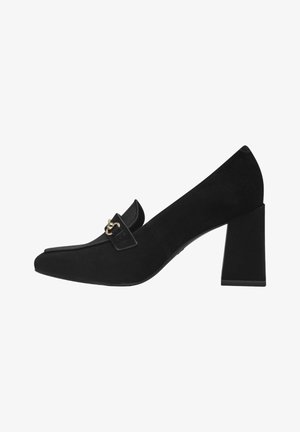 Zapato de tacón cuadrado de ante negro con punta afilada, que presenta una tira decorativa y un detalle de hardware en tono dorado. Textura suave, diseño minimalista.