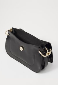 Sac à main en cuir noir avec une texture lisse, une forme arrondie, une fermeture magnétique sur le dessus et des accents en métal doré. L'intérieur n'est pas doublé.