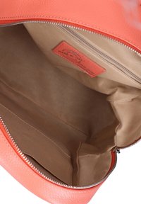 Sac à main en cuir corail avec fermeture éclair. L'intérieur est doublé de tissu beige, comprenant une petite poche pour cartes et une texture lisse.