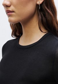 Zwart topje met een ronde halslijn en korte mouwen, gemaakt van een glad, nauw aansluitend materiaal; heeft een subtiele textuur en een strak ontwerp.