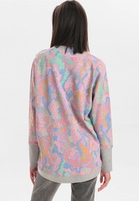 Sweat-shirt ample aux teintes pastel multicolores, doté d'un motif abstrait texturé et de manches longues avec des poignets contrastants.