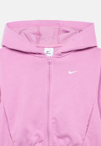 Sudadera con cremallera rosa, fabricada en tela suave, que presenta una capucha, logo blanco de Nike y textura acanalada. Incluye bolsillos laterales y cintura elástica.
