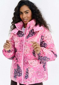 Różowa kurtka puchowa z kwiatowymi i paisley wzorami, zapinana na zamek z przodu, z regulowanym kapturem i elastycznymi mankietami. Miękka, pikowana faktura.