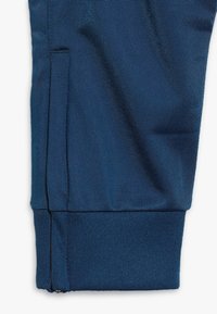 Die Marineblauen Sportpants verfügen über ein tailliertes Design, ein strukturiertes Material, einen Reißverschluss am Knöchel und seitliche Taschen für Stauraum und Komfort.