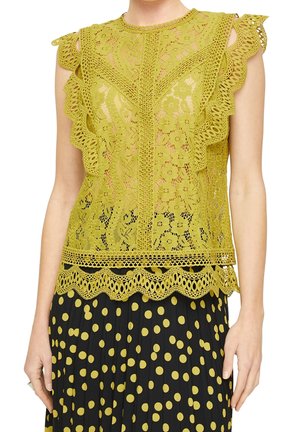 Ärmeløs gul blondebluse med blomstermønstre og buede kanter, kombineret med en sort plisseret nederdel med gule prikker.