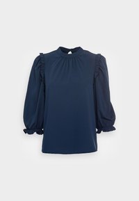 Blusa blu scuro con colletto alto, scollatura arricciata e maniche a sbuffo. Presenta dettagli a volant lungo le spalle e polsini elasticizzati.