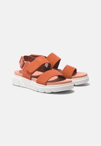 Orange suede sandals with white rubber sole, featuring wide straps and a back strap for secure fit. Flat design with minimalistic accents.