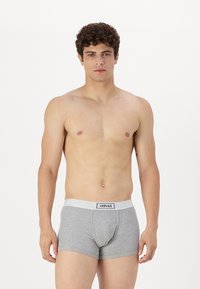 Boxeri din bumbac gri cu un tiv elastic alb pe care este afișat logo-ul "VERSACE", având un design ajustat și o textură netedă.