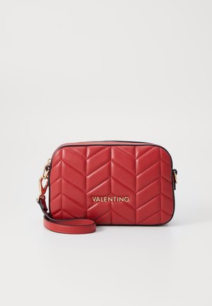 Bolso de cuero acolchado rojo con un patrón de chevron, logo dorado, cierre con cremallera y correa desmontable. Textura suave y forma rectangular.