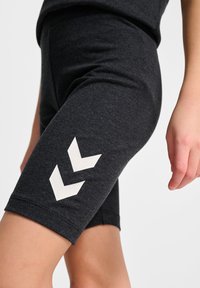Mörkgrå bomullsblandning cykelshorts med en åtsittande design. Har vita chevronmönster på låret. Slät textur och knälång.