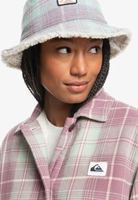 Randig bucket-hatt i pastellgrön och lila med en fluffig vit foder. Har en logotypapplikation på framsidan.