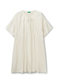 Camisa de manga corta color crema con un diseño fruncido y un cuello con lazo, que presenta una tela texturizada y un detalle de costura decorativa.