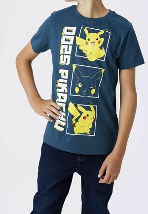 Dziecko noszące niebieską koszulkę z trzema ilustracjami Pikachu i pionowym napisem "Pikachu 025" na przodzie.