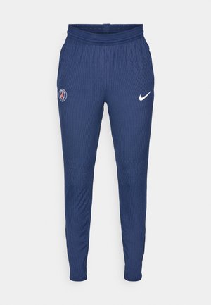 Sötétkék sportnadrág, amely texturált anyagból készült, bal combján Párizs logóval, míg a jobb lábszáron egy fehér Nike pipa látható.