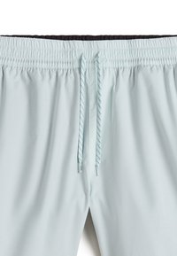 Helle blaue Badehose mit elastischem Bund, innen schwarz und einem Kordelzug mit gestreiftem Muster. Glatte Oberfläche, keine Taschen.