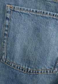 Tela de mezclilla azul con un bolsillo trasero con costuras amarillas, que muestra una textura ligeramente desgastada y sutiles variaciones de color.