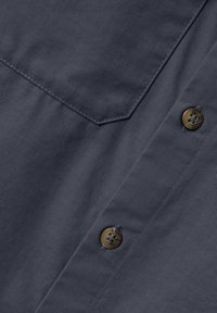 Camicia button-down blu navy in tessuto texturizzato con motivo a griglia, rifinita con bottoni marroni e una tasca appuntita.