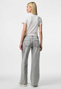 Sive široke traperice s visokim strukom, velikim strašnjim džepovima i izbjeljenim završetkom, uparene s običnom bijelom majicom kratkih rukava.