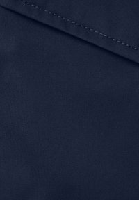 Navy blue fabric, tightly woven with a smooth texture, features a diagonal fold at the top and contrasting white stitching along the edge.