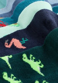 Kootud kangas värviliste dinosaurusmustritega rohelisel, roosal ja punasel, mille taustal on mereväe, tumesinised ja helesinised triibud, mis loovad tekstuurse laineefekti.