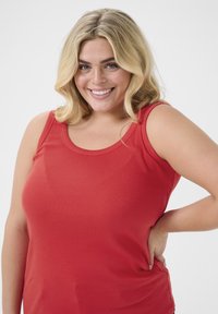 Red ribbed tank top with wide straps and a round neckline, featuring a close fit and smooth texture.