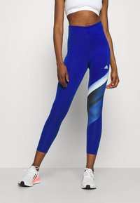 Blå atletiska leggings gjorda av elastiskt tyg, med hög midja och abstrakt ljusblå och svart grafisk mönstring på sidan.