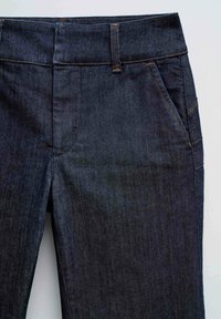 Vaqueros de mezclilla oscura con una textura suave, diseño de cinco bolsillos y costuras en contraste. La cinturilla es de altura estándar y no tiene marcas visibles.
