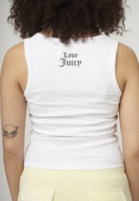 Bijela rebrasta majica bez rukava s natpisom "Love Juicy" otisnutim crnim gotičkim fontom na leđima, koja prikazuje uski kroj i meku teksturu.
