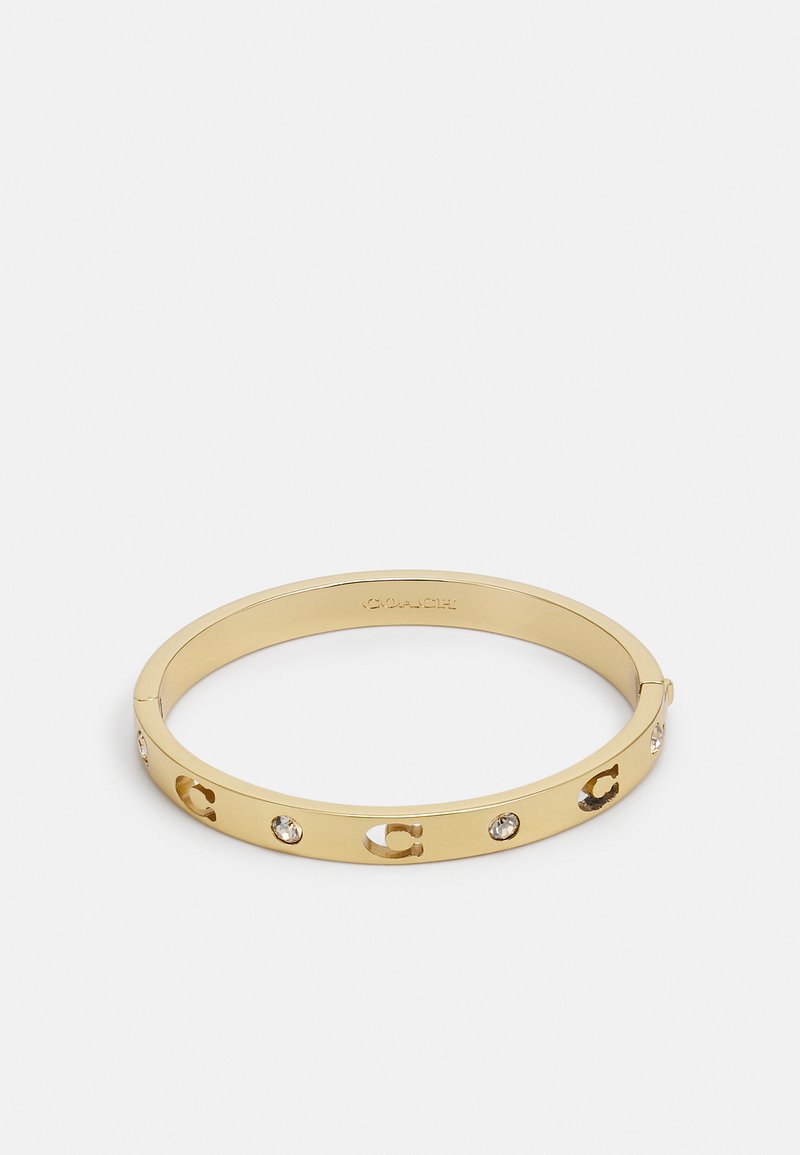 Gold metal bangle bracelet featuring cut-out letters and embedded clear crystals. Smooth, shiny texture with a simple, round design.