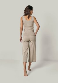 Beige, gerippter Tanktop mit rundem Rücken, kombiniert mit weit geschnittenen Hosen bis zur Mitte der Wade. Weicher, strukturierten Strickstoff.
