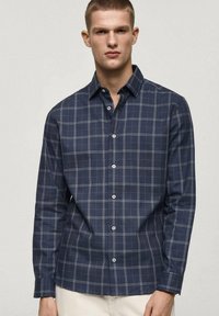 Marineblauw geblokt overhemd in een lichtgewicht stof met een button-down kraag, voorzien van witte knopen en groene accenten in het ruitpatroon.