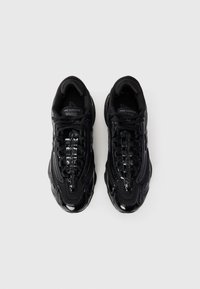 Black sneakers with a textured synthetic upper, featuring glossy accents and streamlined design. Shoes have a cushioned sole and lace closure.