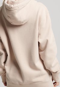 Lichtbeige hoodie met een relaxed fit, voorzien van een capuchon met trekkoord, geribbelde manchetten en zoom, en een zachte fleecevoering aan de binnenkant.