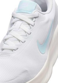 Zapatilla deportiva blanca con un upper de malla texturada y acentos en azul claro. Presenta una lengua acolchada y cordones. Incluye un logo en forma de swoosh.