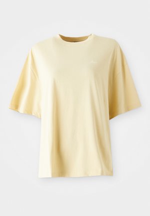 T-shirt en coton jaune avec une coupe ample, des manches courtes, un col rond et un logo brodé discret sur le côté gauche à l'avant.