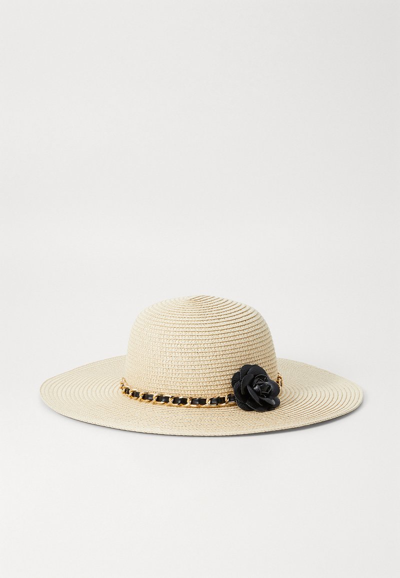 Beige Strohhut mit breiter Krempe und strukturierter Webart, ausgestattet mit einem schwarzen floralen Akzent und einem goldfarbenen Kettenband.