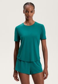 Turquoise, rövid ujjú póló sima anyagból, hozzá illő rövidnadrággal párosítva. A dizájn kerek nyakkivágással és laza fit kialakítással rendelkezik.