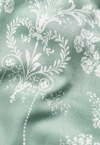 Fabric featuring a soft mint green background with a detailed white floral and vine pattern, showcasing intricate textures and designs.