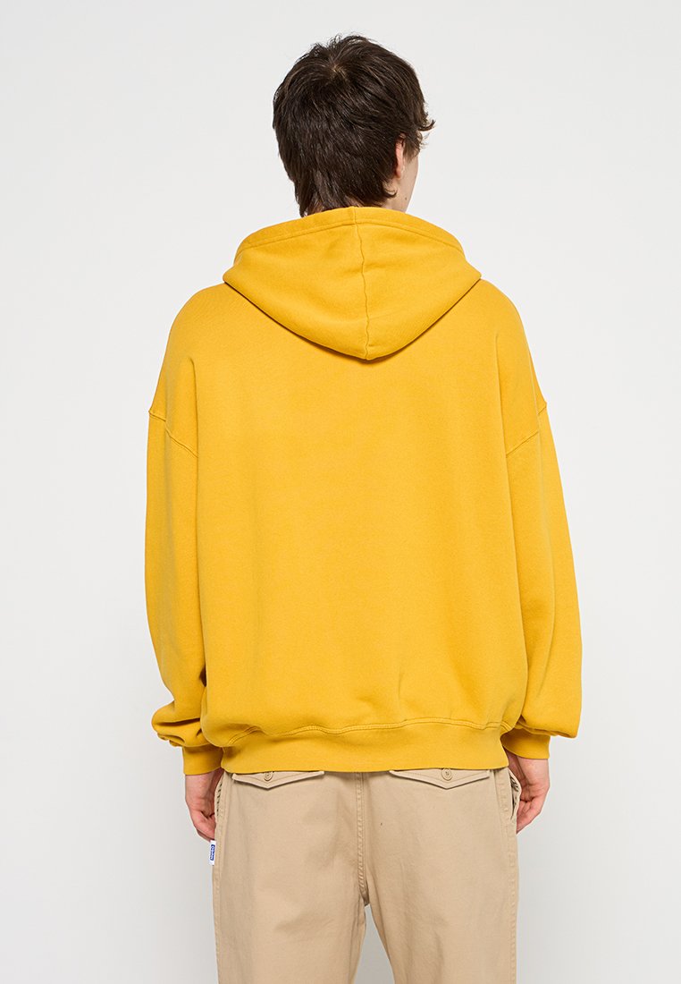 Geel hoodie met een losse fit, ribbelmanchetten en -zoom, gemaakt van zachte stof. Zichtbare stiksels en een casual ontwerp.