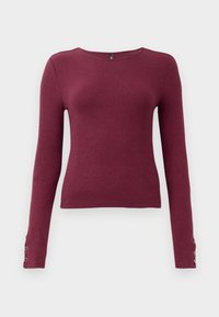 Pull en maille côtelée à manches longues bordeaux avec un col rond et des accents de boutons sur les poignets. Fabriqué dans un matériau en tricot texturé.