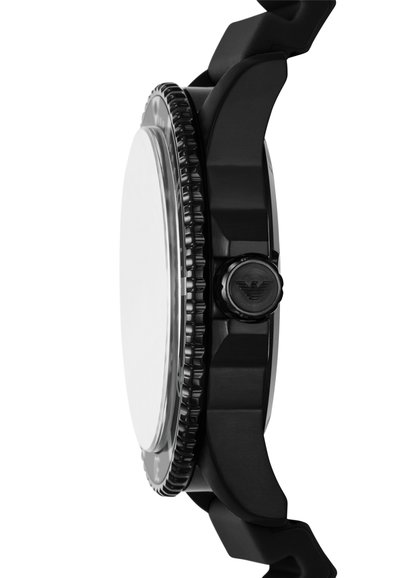 Montre noire au design massif, bracelet en plastique lisse, lunette texturée et boîtier rond. Présente une couronne proéminente avec un détail de logo.