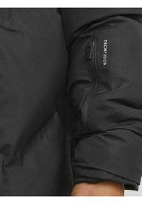 Schwarzer Puffer-Jackenärmel mit einer Reißverschlusstasche und dem Text "TECHFUSION". Das Material wirkt glatt und leicht glänzend.