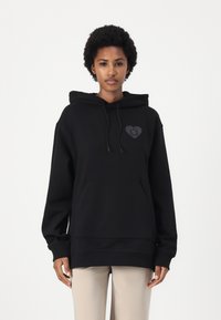 Black hooded sweatshirt in soft fabric, featuring a front pocket and a heart-shaped logo with a smiley face. Relaxed fit, long sleeves.
