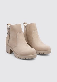 Botines de ante beige con punta redonda, cremalleras laterales y suelas de goma texturizadas, que cuentan con un tacón de bloque grueso.