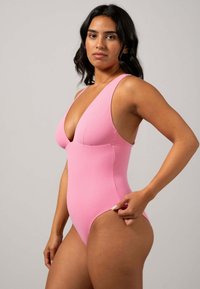 Roze badpak met een diepe V-hals, brede banden en hoge beenopeningen. Gladde textuur en aansluitende pasvorm.