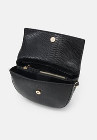 Černá crossbody taška s hadím vzorem, s magnetickým uzávěrem, zlatou kapsou na zip a nastavitelným uchem. Interiér je podšitý.