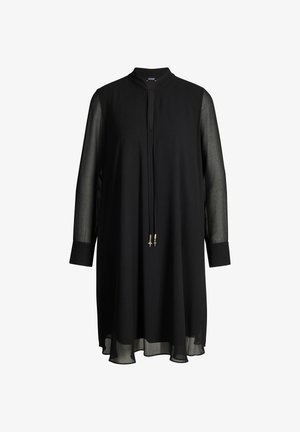 Zwarte jurk tot op de knie met doorschijnende lange mouwen, hoge kraag en een strik aan de voorkant met metalen uiteinden in de vorm van sterren.