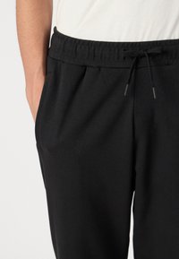 Sorte sweatpants med elastisk talje, snor og sidelommer, der har en glat tekstur og en afslappet pasform.