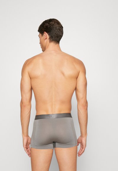 Grå boksershorts laget av mykt materiale, med en glatt linning og en tettsittende design, vist fra baksiden.